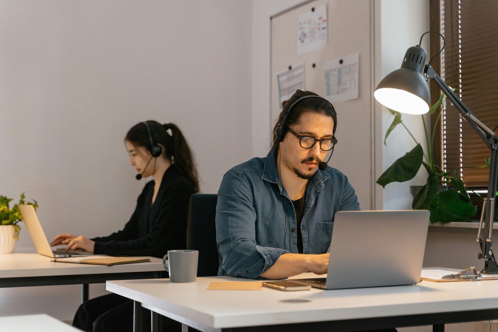 Ejecutivo de soporte TI trabajando con headset y laptop